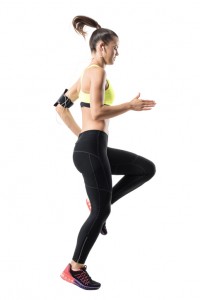 Frozen motion of fit female athletic runner doing high knees warm up exercise.