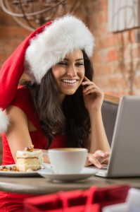 Beautiful young woman wearing Santa's hat using laptop